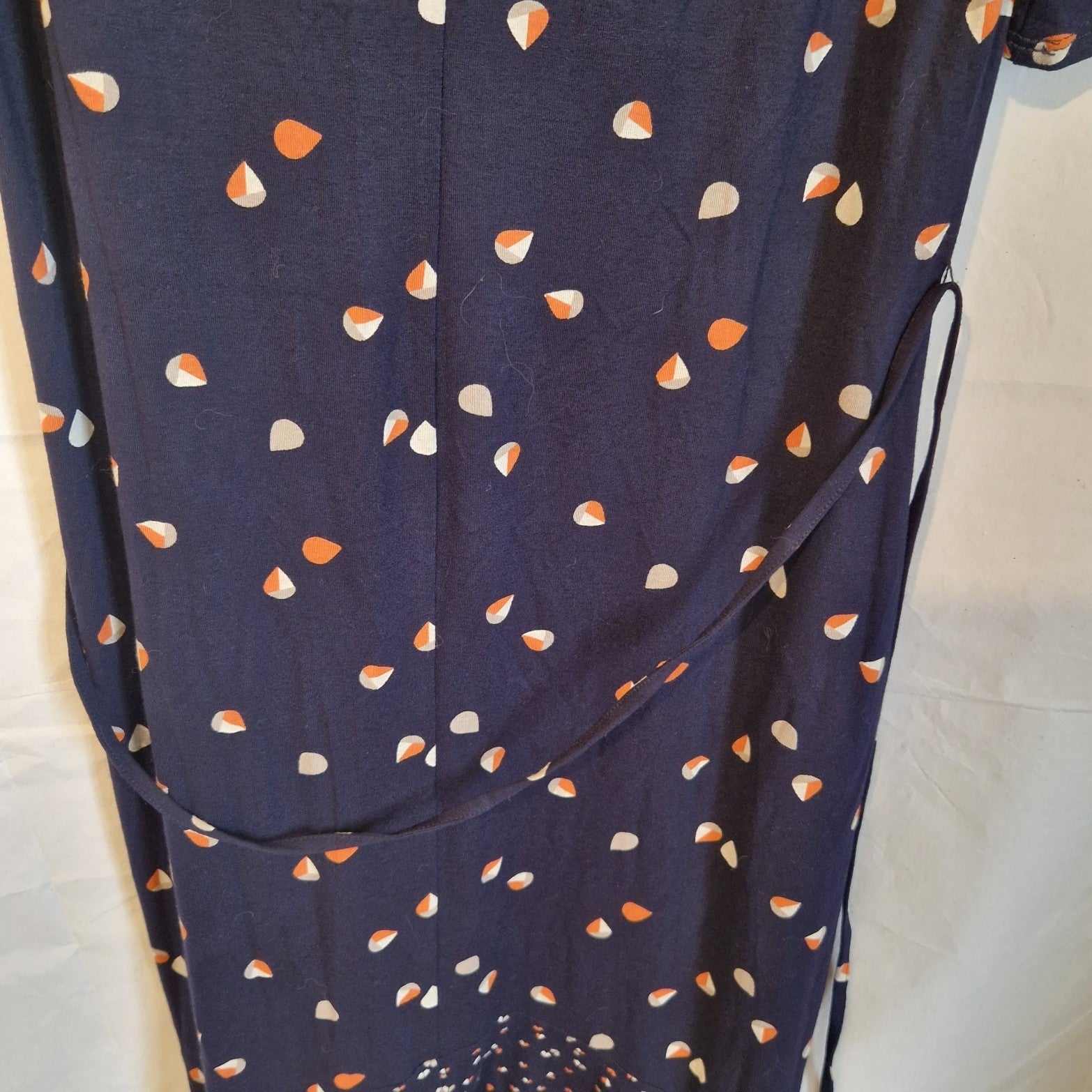 A navy blue fit and flare dress featuring a small multicoloured teardrop print and a waist tie.