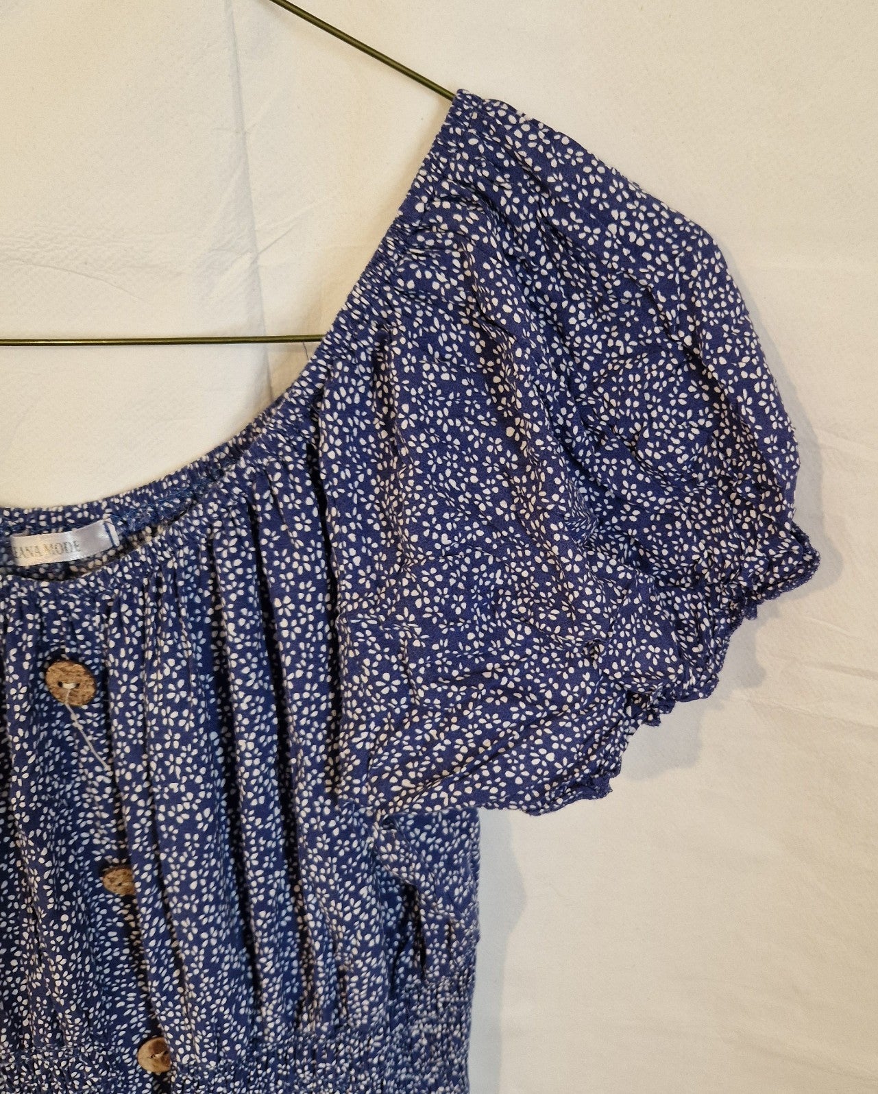 A blue Leana Mode knee-length dress with a white floral pattern, puff sleeves, and button accents.