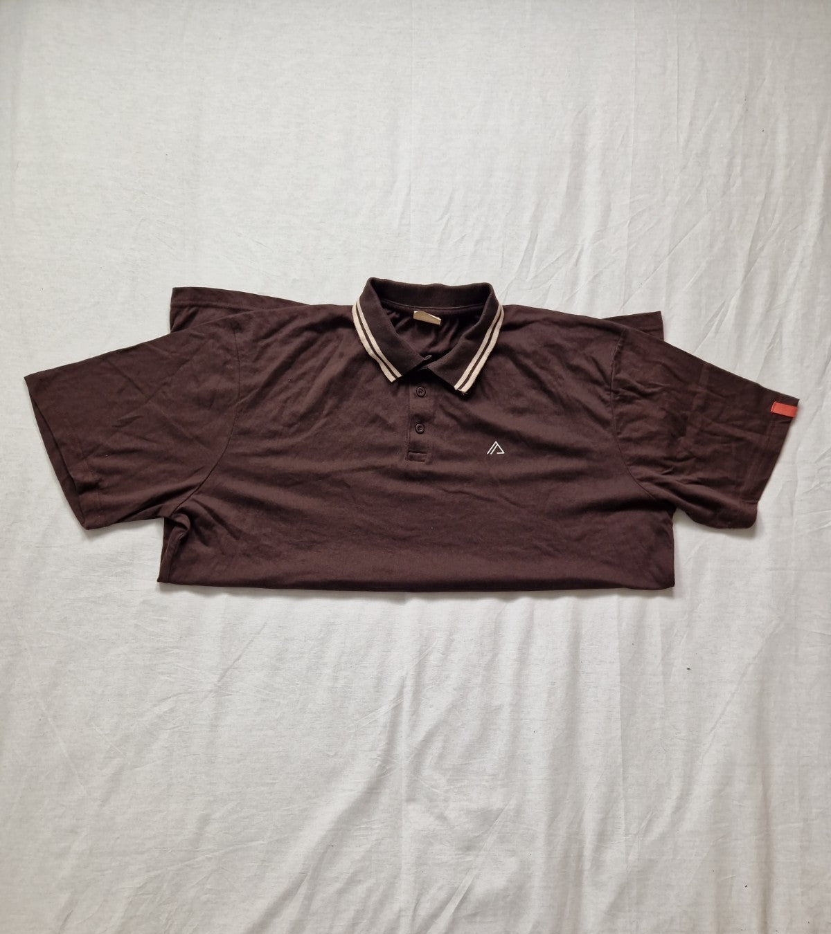 Brown polo shirt on a light gray bedspread