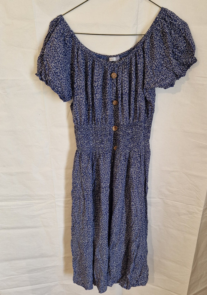 A blue knee-length dress with a white floral pattern, short puff sleeves, and button accents.