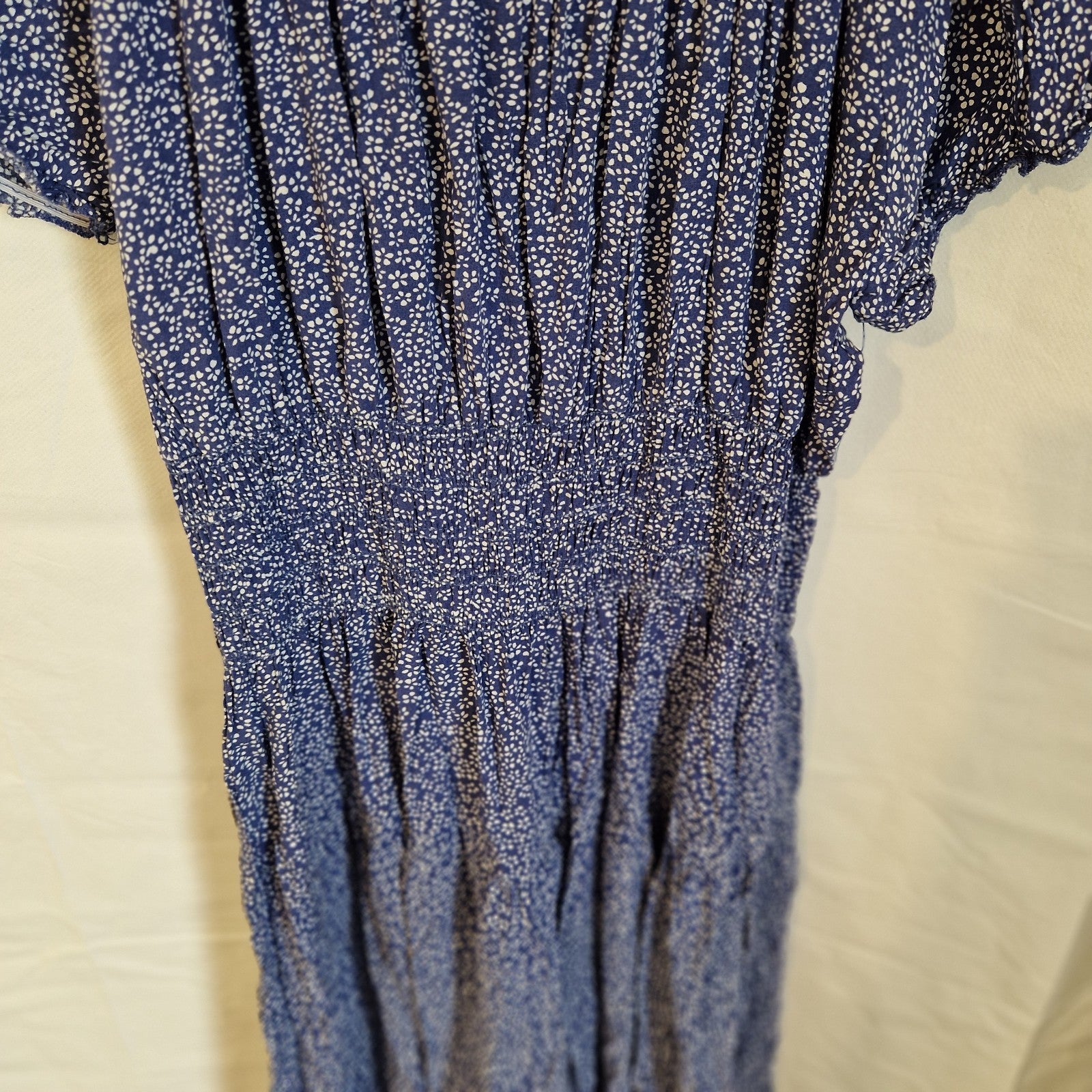 A blue knee-length dress with a white floral pattern and a smocked elastic waist.
