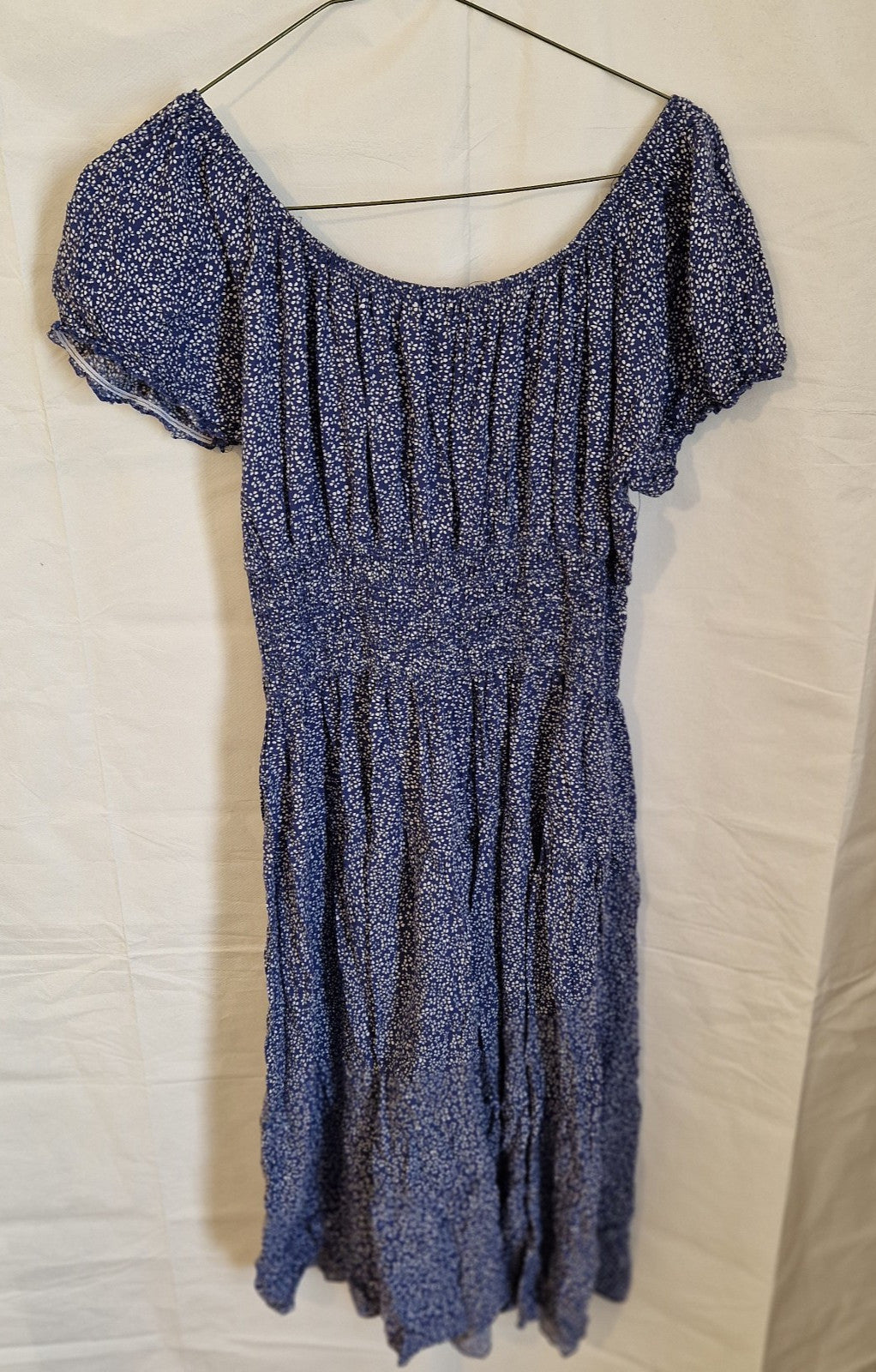 A blue knee-length dress with a white floral pattern, short sleeves, and a smocked waist.